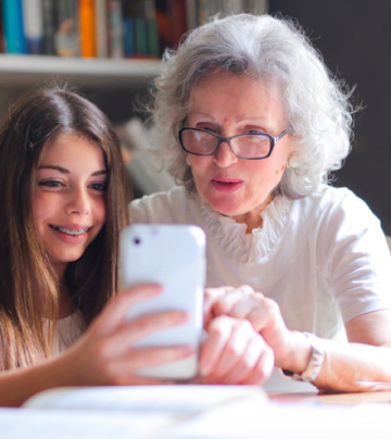 A picture of an elderly woman with a young woman looking at a mobile device